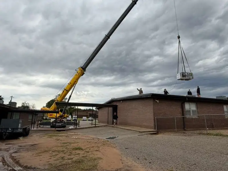 Crane lifting a rooftop unit onto a commercial building
